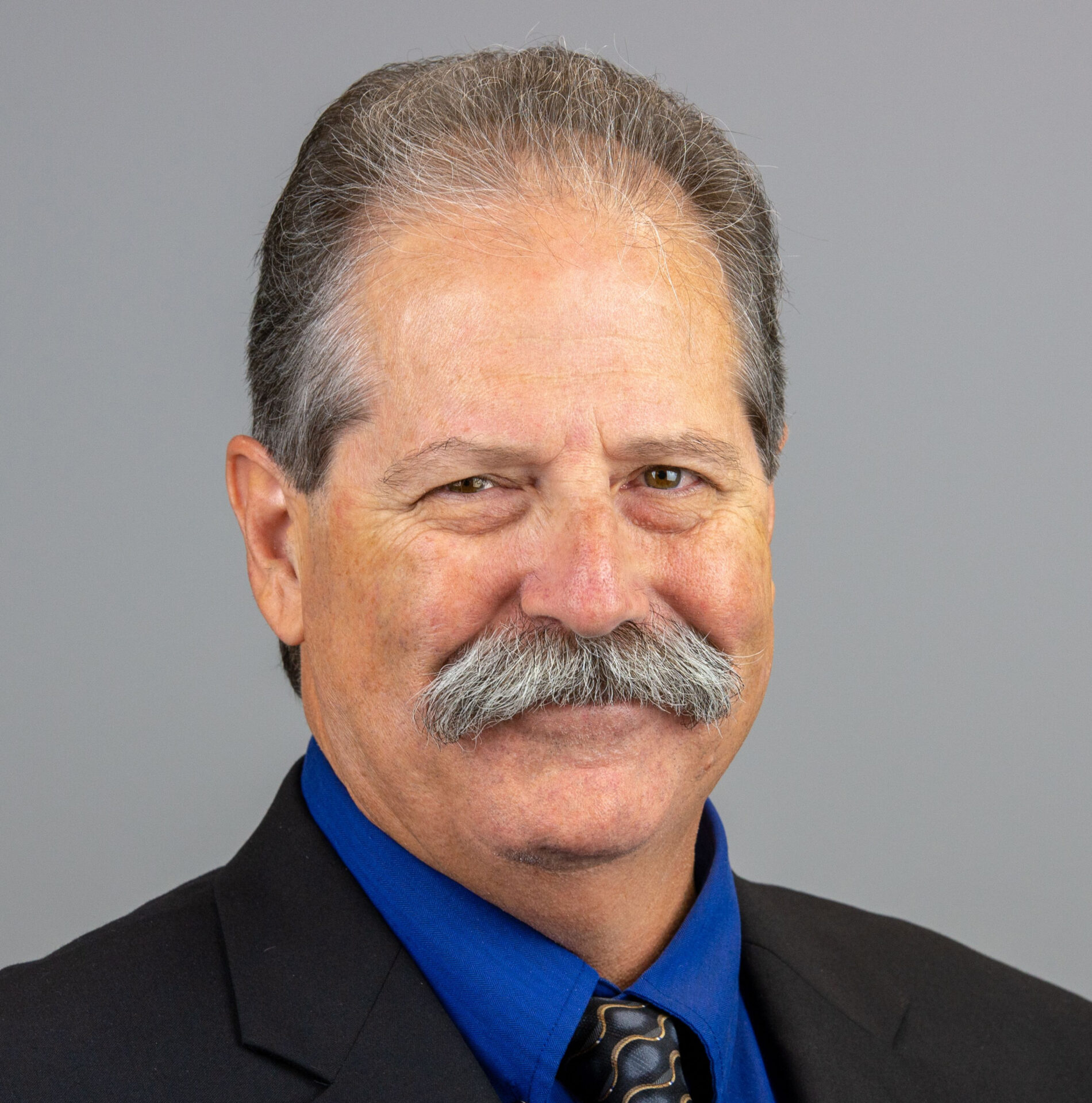 A man with a mustache and suit jacket.