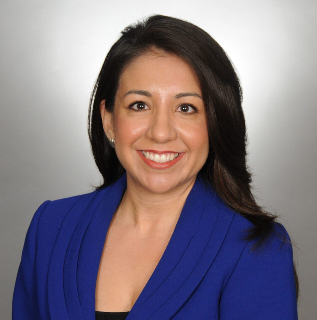 A woman in blue jacket smiling for the camera.